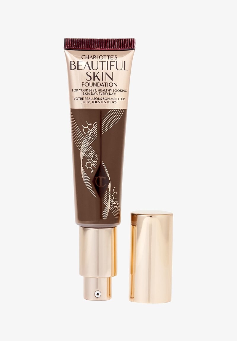 Tube of Charlotte's Beautiful Skin Foundation with gold pump and cap, brown and beige packaging, floral design, text in English and French.