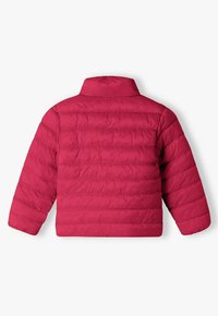 Röd vadderad jacka med hög krage, med horisontell quiltad textur och långa ärmar. Inga synliga spännen eller fickor.