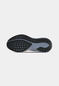 Outsole of a running shoe with black rubber tread and gray midsole featuring a Nike logo and grip pattern on a white background.