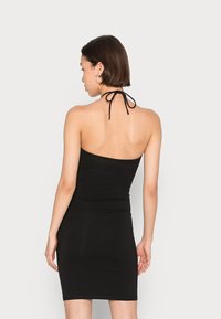 Vestido mini preto com um design ajustado, laços nas costas e textura suave, sem mangas e com uma bainha até aos joelhos.