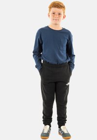 Camisa azul de manga larga con un bolsillo frontal, pantalones jogger negros y zapatillas grises con suelas naranjas. Diseño sencillo, ajuste casual.