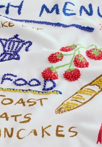 Håndbroderet stof med farverige perler, der danner jordbær, en blå tekande, en grissini og madord som "MAD" og "PANDEKAGER".