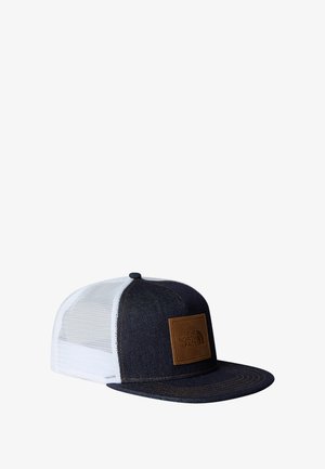 Denim pet met een donkerblauwe voorkant, witte mesh zijkanten, een bruin leren logo patch en contrasterende stiksels op de rand.