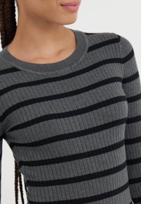 Pull gris à côtes avec des rayures horizontales noires, doté d'un col rond et d'une texture douce. Le design met l'accent sur une silhouette ajustée.
