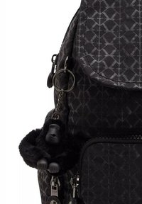 Black backpack made of textured fabric featuring a geometric pattern and a plush black gorilla keychain attached to a zipper.