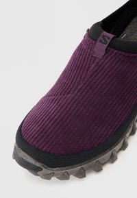 Ljubičaste corduroy slip-on cipele s crnim obrubom, sivim robusnim potplatom i tkaninom za povlačenje na peti.