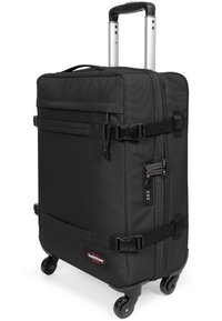 Black wheeled suitcase made of durable fabric, featuring a telescopic handle, two zipper compartments, and side buckle straps for secure closure.