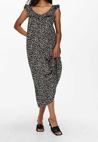 Černé květinové šaty s malými bílými a růžovými květy, s volánkovými rukávy a volným střihem. Kombinované s černými otevřenými mule sandály.