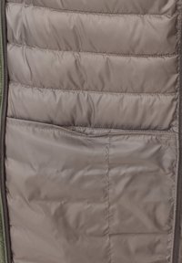 Braune Pufferjacke mit gestepptem Innenfutter, die mehrere Taschen und ein glattes Futter aufweist. Reißverschluss entlang des Randes.