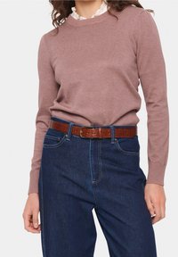 Light pink knitted sweater with long sleeves and ribbed cuffs, worn over dark blue high-waisted jeans, accented with a brown leather belt.