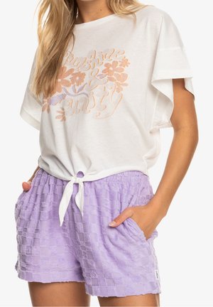 Camiseta de algodón blanca con diseño floral en tonos pastel, combinada con pantalones cortos de lavanda con textura, cintura con lazo y bolsillos laterales.