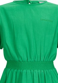 Green dress made of textured fabric, featuring short sleeves, a smocked waist, and a keyhole back with a tie closure. "Retour Jeans" embroidered.