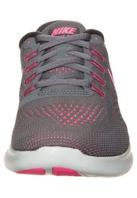 Szare buty sportowe z różowymi akcentami. Siatkowa cholewka, okrągły czubek i płaskie sznurówki. Gruba, wyściełana podeszwa z różowym detalem na podeszwie.