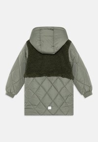 Quiltad huva jacka i ljusgrön med panel av mörkgrön faux päls. Har elastiska ärmslut och en fyrkantig logotyp på baksidan.