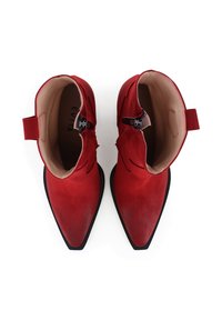 Bottines en daim rouge avec bouts pointus, semelles en caoutchouc noir et zip latéral. L'intérieur est doublé d'une matière lisse de couleur beige.