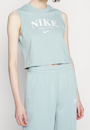 Crop top Nike bleu clair sans manches avec le texte « Athletic dept. 1972 », associé à un pantalon bleu clair assorti avec une taille élastique.