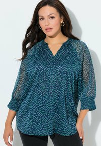 Tmavě modrá halenka s výstřihem do V, zdobená zelenými vzory připomínajícími srdce, průhlednými rukávy a nařasenými manžetami. Měkký, lehký materiál.