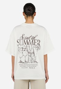 Camiseta blanca de gran tamaño con un dibujo en línea negra de bebidas y texto que dice "Aroma de Verano" en la parte posterior. Manga corta.