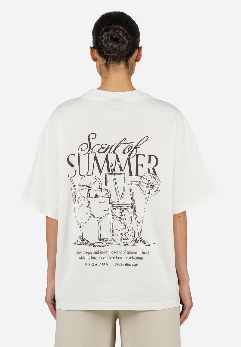 Camiseta blanca de gran tamaño con un dibujo en línea negra de bebidas y texto que dice "Aroma de Verano" en la parte posterior. Manga corta.