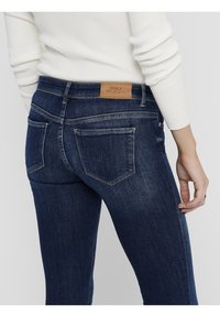 Tmavě modré džíny ze silné denimové tkaniny s těsným střihem, které mají koženou nášivku s označením "ONLY" na zadním pasu a dvě zadní kapsy.