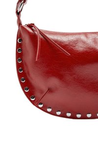 Czerwona skórzana torebka o zaokrąglonym kształcie, ozdobiona srebrnymi ćwiekami wzdłuż krawędzi oraz wąskim skórzanym paskiem do noszenia.