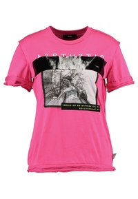 Rosa t-shirt med kort ärm och en svart horisontell panel med grafiskt tryck. Sliten fåll och rullade ärmar. Material av bomull.