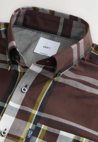 Camisa de cuadros marrón con rayas gris, blanca y amarilla. Corte regular, con cuello abotonado y etiqueta de marca.