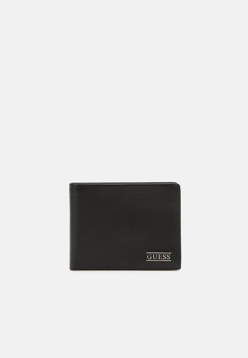 Black leather wallet with a smooth texture, bi-fold design, and a gold-tone "GUESS" logo at the bottom right corner.