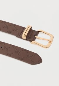 Καφέ δερμάτινη ζώνη με ανάγλυφα κυκλικά μοτίβα, με αγκράφα και καρφί από μεταλλικό υλικό σε χρυσό χρώμα, λεία υφή και στενόμενο άκρο.