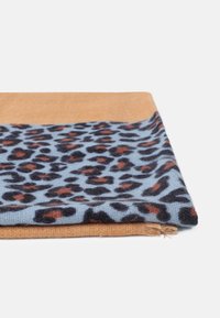 Écharpe pliée avec des bords beige et un centre bleu clair présentant un motif léopard noir et brun rouille sur fond blanc.