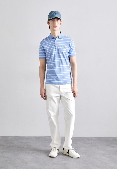 Μπλε ριγέ πόλο μπλούζα με κοντά μανίκια, συνδυασμένη με λευκά παντελόνια ίσιας γραμμής και λευκά αθλητικά παπούτσια. Το καπέλο είναι σε καμβά μπλε. Απλός σχεδιασμός.