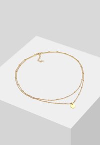 Collana dorata con due catene sovrapposte, decorate con accenti di perline cilindriche e tonde, oltre a un piccolo pendente circolare.