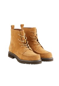 Bottines en daim beige avec un bout rond, un laçage à l'avant et des détails de couture. Semelle épaisse avec un motif de crampons pour une meilleure adhérence.