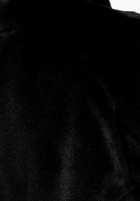 Černá sametová látka s měkkou, hladkou strukturou. Povrch vykazuje mírný lesk, který vytváří jemné odrazy světla. Žádné viditelné vzory ani akcenty.