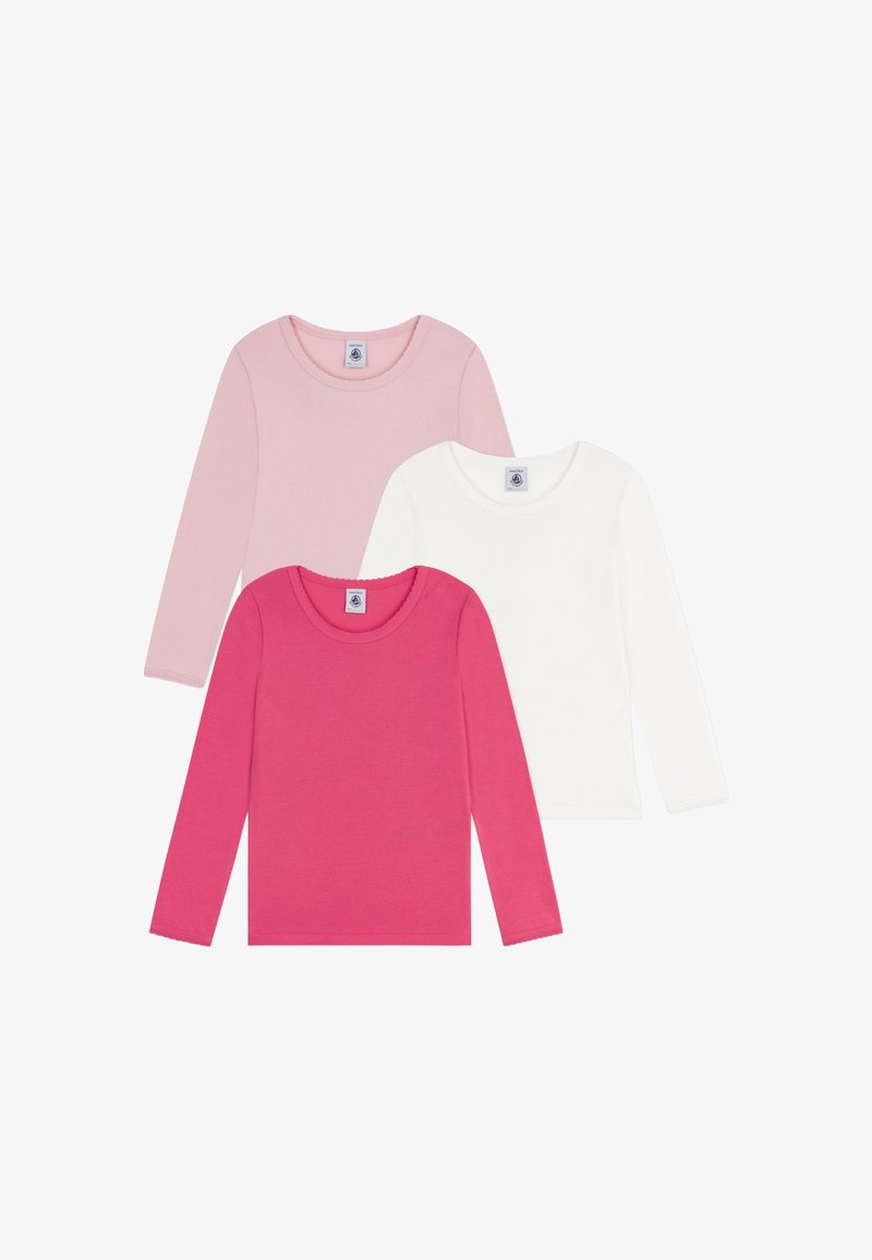 Tre langermede crew neck t-skjorter i rosa, lys rosa og hvit bomull, med merker ved utringningen og glatt tekstur.