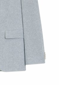 Manche de blazer gris clair et poche avant avec un motif subtil de fines rayures verticales et trois boutons de couleur claire sur le poignet.