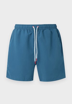 Blå badeshorts med elastik i taljen og hvid snor med røde ender, vist fladt på en lys grå baggrund.