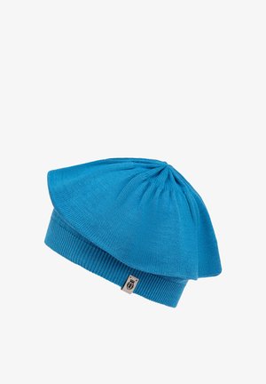 Blue knit hat with a flared top and ribbed cuff. Features smooth texture, intricate stitching, and a small branded tag on the side.