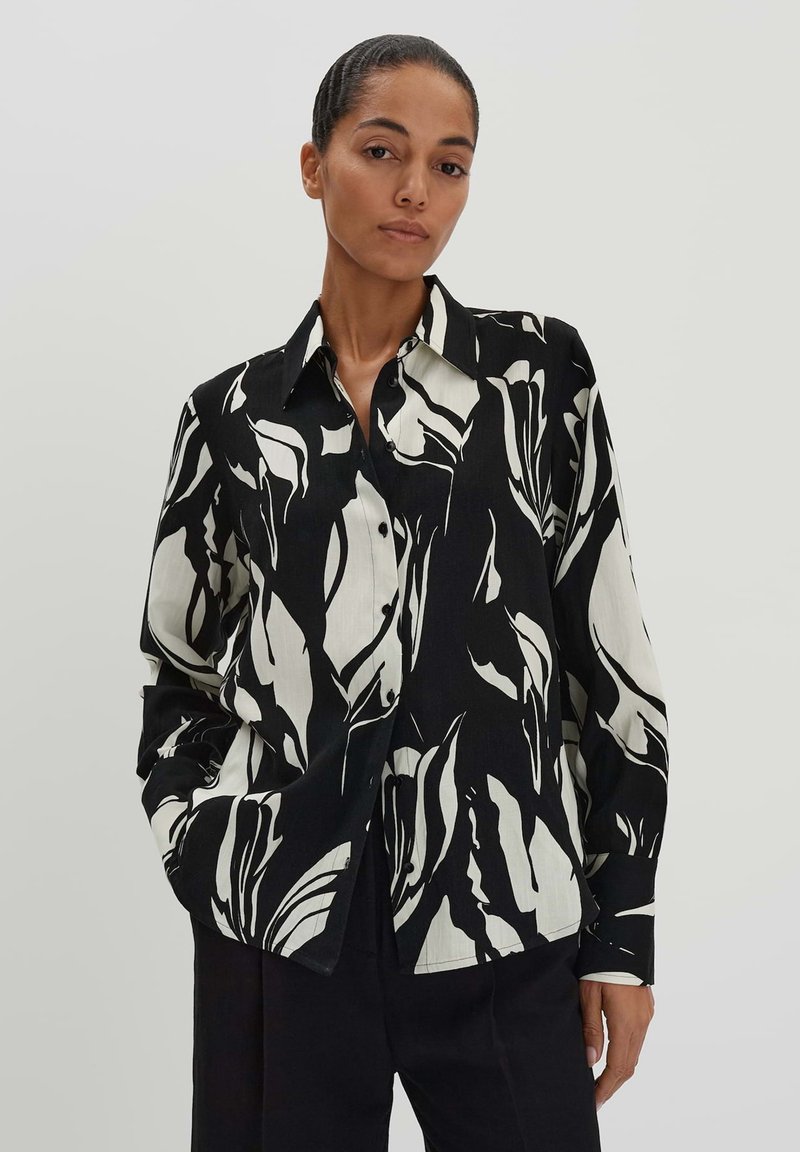 Camicia a maniche lunghe bianco e nera con un audace motivo astratto di foglie, colletto strutturato. Tessuto liscio.