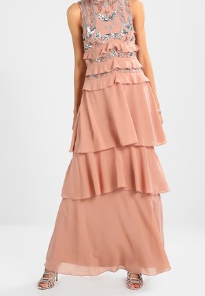 Ærmeløs fersken maxi-kjole med lagdelte flæser og sølv blomsterbroderi på overdelen, kombineret med sølv høje hæle med stropper.