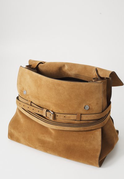 Geantă din suede maro cu o formă structurată, compartiment principal mare și un accent cu curea. Include accesorii metalice și o textură netedă.