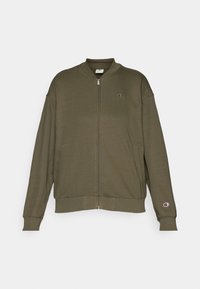 Olivgrüner Zip-Up-Hoodie aus weichem Stoff, mit Stehkragen, zwei seitlichen Taschen und einem kleinen Logo auf der Brust.