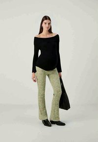 Black off-the-shoulder ribbed top, green textured flared pants, and black handbag. The pants feature a subtle woven pattern and are fitted at the waist.