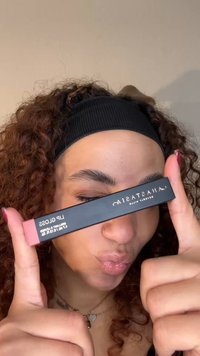 Anastasia Beverly Hills lipgloss in een slanke rechthoekige zwarte tube met roze accenten. De gloss lijkt glanzend en reflecterend op de lippen van het model.