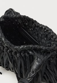 Czarna torebka z plecionki skórzanej o teksturowanym wykończeniu, z frędzlami i plecionymi detalami na krawędzi oraz uchwytach.