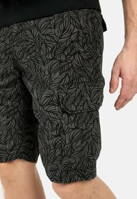 Cargo shorts in donkergrijze stof met een zwart bladerenpatroon; heeft zijzakken en een ontspannen, losse pasvorm.