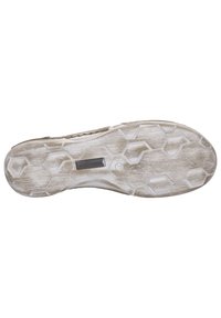 Semelle de chaussure de couleur blanche et gris clair, présentant un motif de bande de roulement hexagonal, une surface texturée et une petite plaque logo en métal.