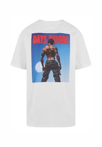 White t-shirt featuring a graphic print on the back. The design shows a figure with a muscular build against a blue background and text "DAYS BEFORE" in red.
