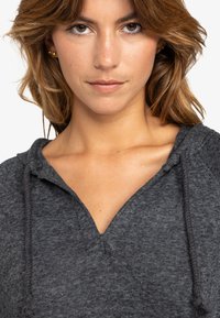 Gray hooded sweatshirt with a v-neck design, featuring a textured fabric and drawstrings at the neckline. Close-up of the collar area.