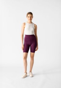 Shorts da ciclismo viola a vita alta abbinati a un top senza maniche bianco. Tessuto liscio con una vestibilità aderente, progettati per l'abbigliamento sportivo.